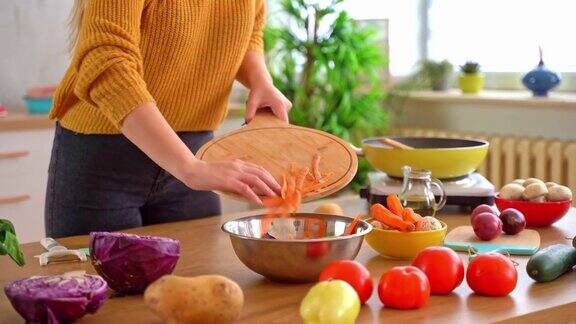 近距离的妇女把胡萝卜屑和其他剩菜放在碗里做堆肥