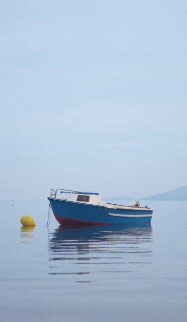 雾蒙蒙的清晨海边小船的宁静景象