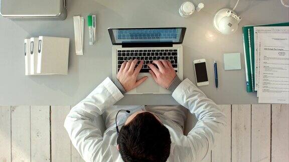 医疗工作者的俯视图与笔记本电脑医生使用键盘工作