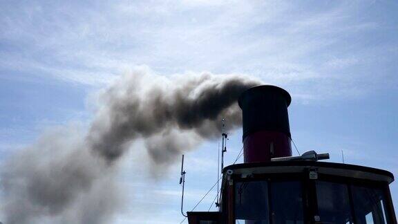 蓝色的天空中黑烟从烟囱里冒出来