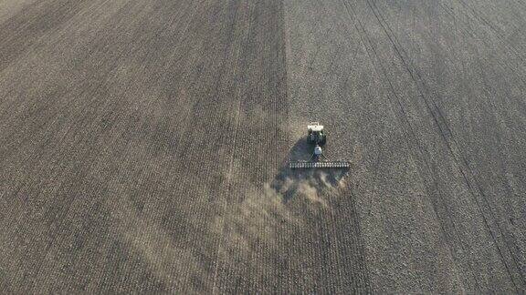 无人机在农田上跟随一辆带免耕播种机的拖拉机