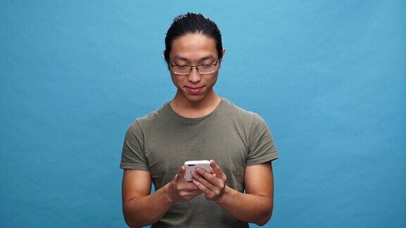 穿着t恤戴着眼镜玩智能手机的快乐亚洲人