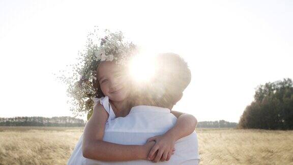 小女孩欢快的拥抱着慈爱的父亲在大自然的麦田里在乡村生活