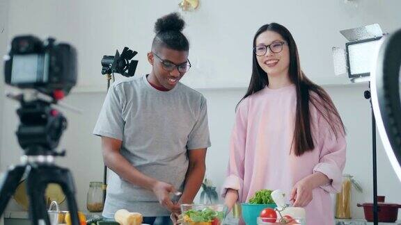 一位年轻女士和一位非裔美国人正在为摄像机做饭