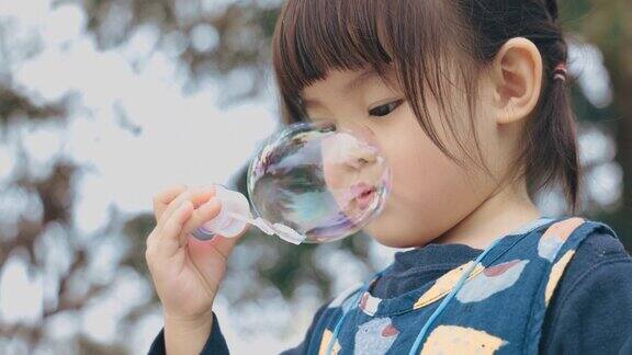 亚洲小女孩在公园里吹泡泡