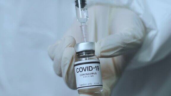医生手持注射器和Covid-19疫苗瓶