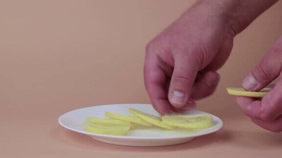 男性的手把一片黄色的柠檬片放在碟子上