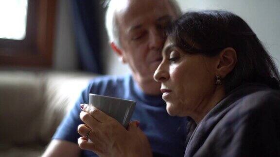 丈夫拥抱发烧的妻子喝着她的热茶