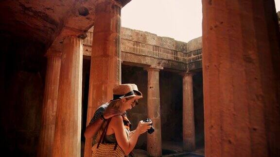 游客拿着相机在希腊的古纪念碑拍照