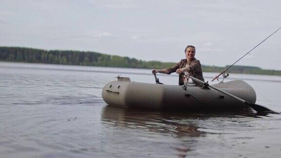 美丽的电影拍摄女渔夫在湖上划着一只充气船