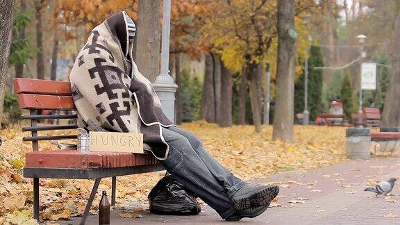 绝望的无家可归者坐在长凳上饥饿的人乞求施舍