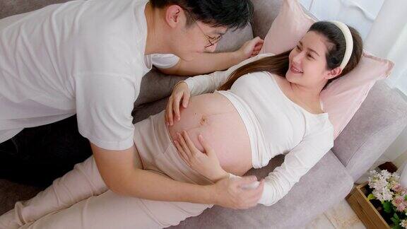 亚洲父亲感动倾听婴儿心跳打击和婴儿移动他怀孕的妻子在家里怀孕家庭生活的爱的时刻