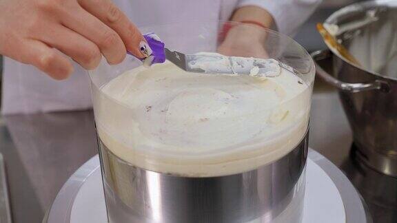 糖果商用烹饪抹刀将白色奶油涂在饼干蛋糕上