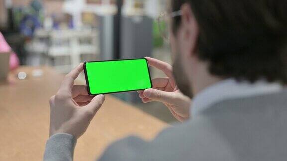 男人看着绿色屏幕的智能手机