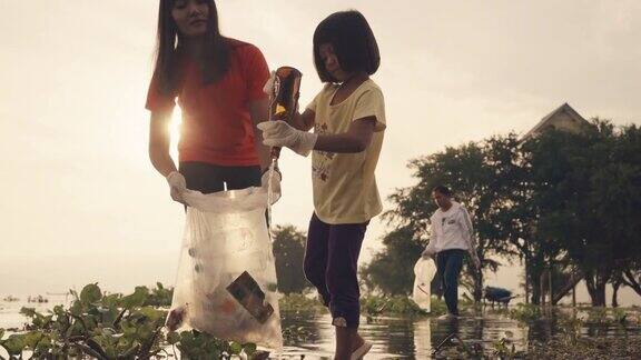 亚洲志愿者家庭晚上在河边收集塑料瓶和水葫芦