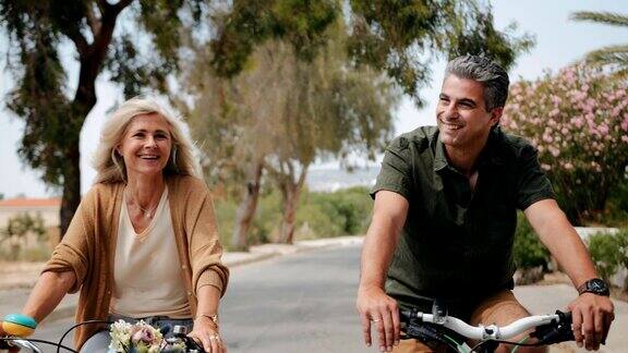 快乐的老年夫妇在郊区的街道上骑自行车在春天