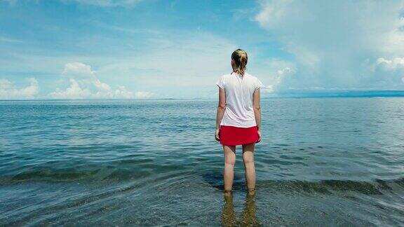 在蓝天的映衬下一个女人站在大海里