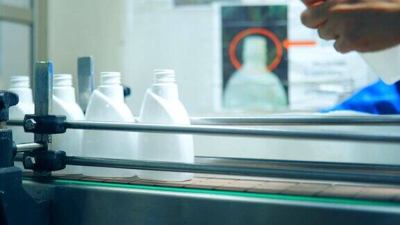 一个女人的手的特写放置白色的空瓶子液体肥皂在传送带在一个化学工厂