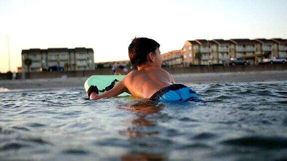 一个小男孩用滑板在海里漂到岸边
