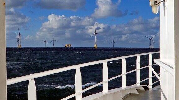 从中转船(船、轮渡)的鼻翼上看航行在狂风暴雨的北海真风电场水平方向上的风力涡轮机