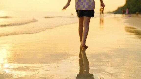 亚洲小女孩在夏天日落的热带海滩上散步和玩耍