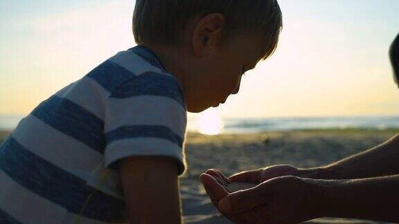 快乐的孩子和父亲在夕阳下的沙滩上玩沙子