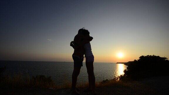 情侣亲吻拥抱夕阳海洋和山脉