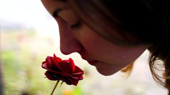 美丽的女孩闻着红玫瑰