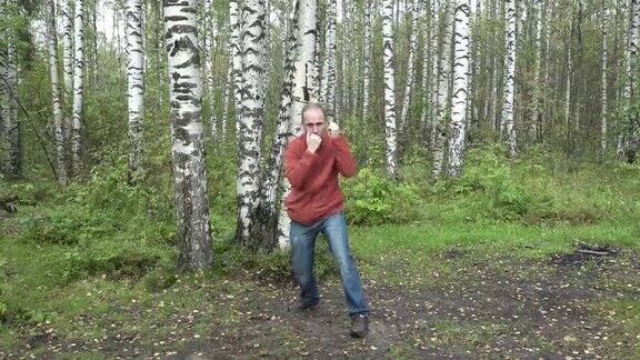 一个穿着休闲装的男人在森林空地上做武术动作慢镜头