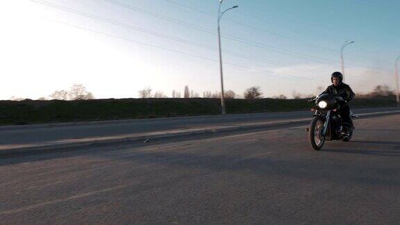 日落时分一个年轻人骑着摩托车在路上行驶慢镜头