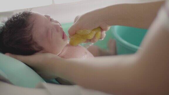 近距离亚洲可爱的新生儿男孩洗澡2-3个月与母亲