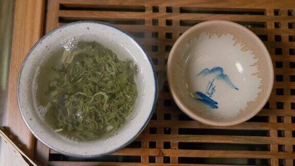 师傅将热水倒入盛有绿茶的碗中盖上盖子从上往下看