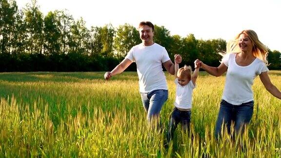 幸福家庭:爸爸、妈妈、儿子穿着白色t恤在田野里奔跑