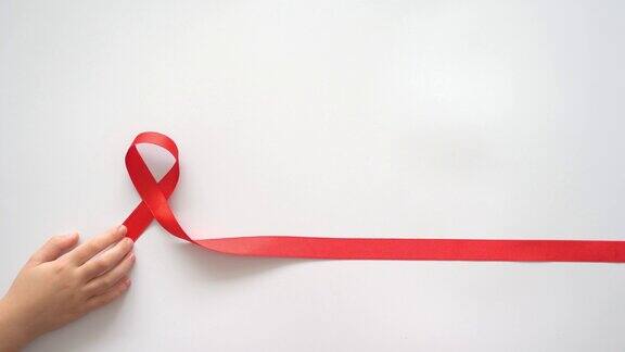 儿童手中拿着白色背景的红丝带象征着与艾滋病毒、艾滋病和癌症的斗争帮助有需要的人慈善捐赠捐赠者4k