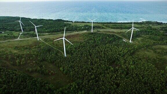 无人机拍摄的日落时分海边森林里的风力涡轮机