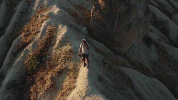 旅行自由无人机在快乐的年轻游客徒步旅行享受卡帕多西亚白色悬崖顶部的景色