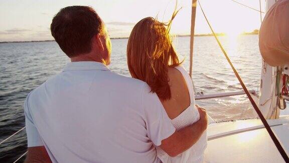 日落时分相爱的白种情侣在游艇上