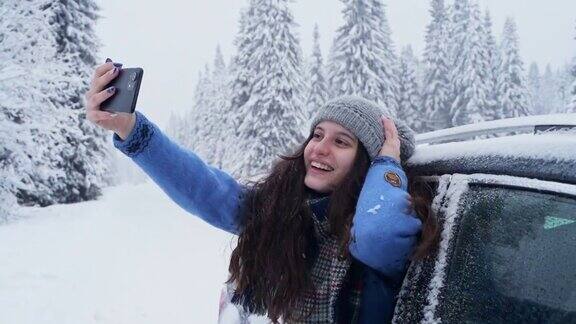 年轻女子在下雪天从车窗里用智能手机