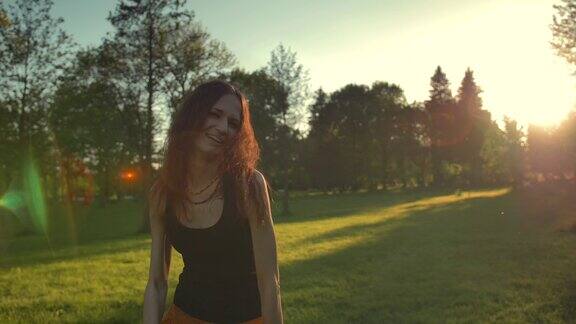 日落时分年轻女子在公园草地上跳舞