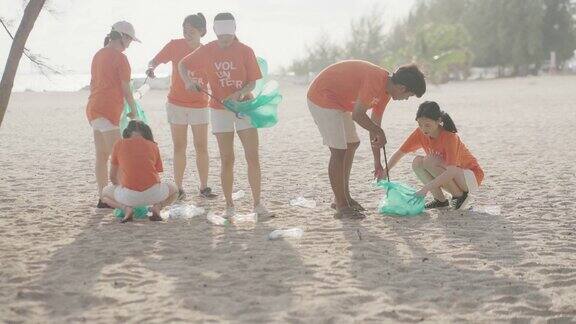 一群带着垃圾袋的Z世代亚洲志愿者在海滩上清理区域
