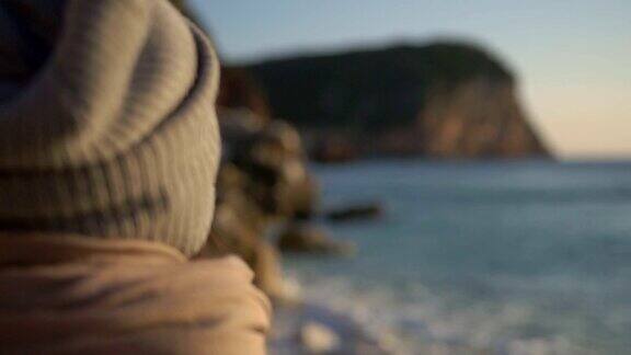 背景女孩戴着帽子看着潮水在日落