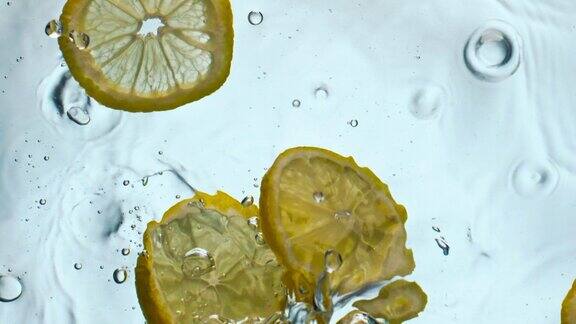 柠檬滴透明水特写黄色维他命果漂浮在液体中