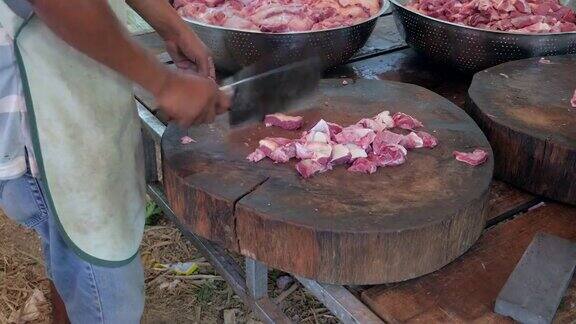 肉贩用切肉刀在圆形木砧板上切一块肉