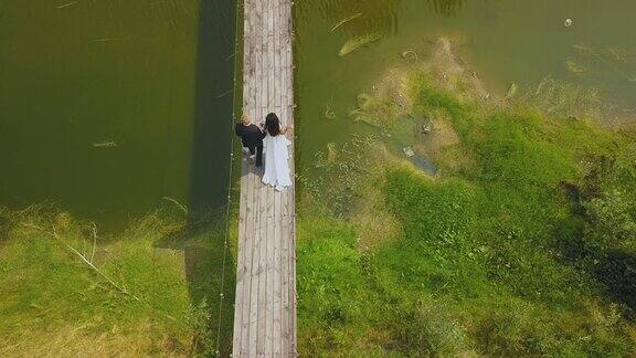 一对新婚夫妇沿着河上架空的旧桥走