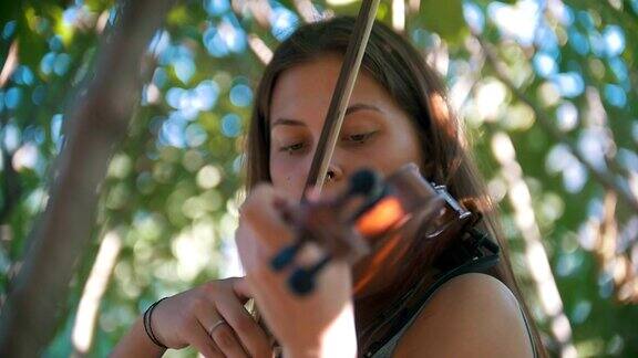 夏日里时髦女孩在公园里拉小提琴