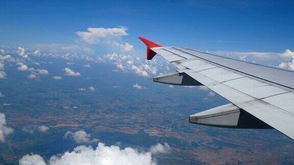 4k乘飞机旅行从飞机窗口鸟瞰机翼飞机和美丽的白云在蓝天旅行背景