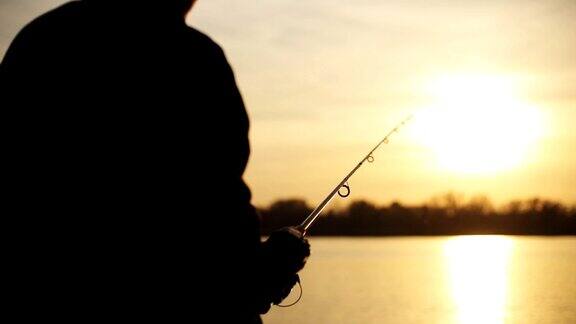 一个渔夫在夕阳下投鱼竿的剪影钓鱼钓鱼运动