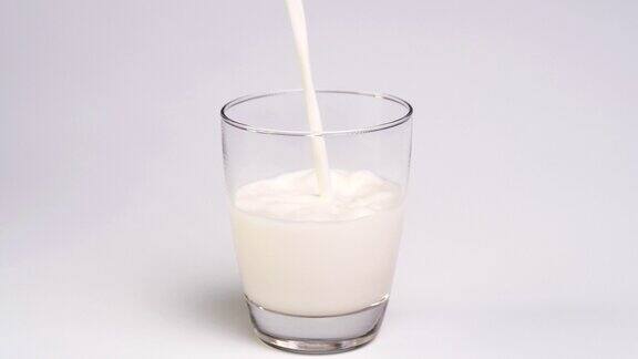 将牛奶倒入白色背景的玻璃杯中
