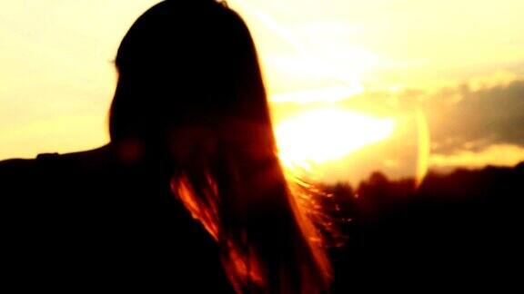 夕阳下一个女人的剪影抚摸着她的头发