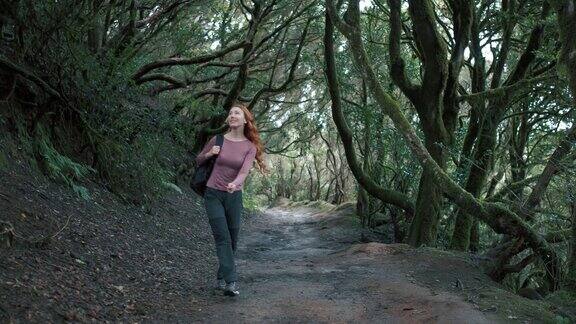 一个女人走在魔法森林里红发长发女孩背着背包